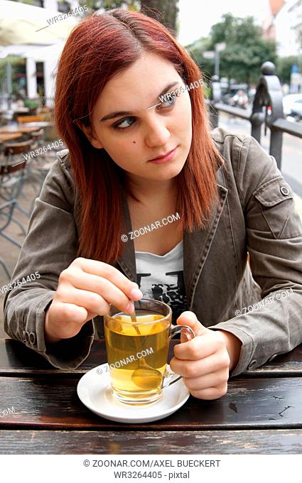 young woman drinking tea in a street cafe