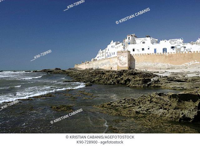 View of the impressive portugese fortification of Essaouira with the surf of the Atlantic Ocean and the white washed buildings and blue doors and window frames...