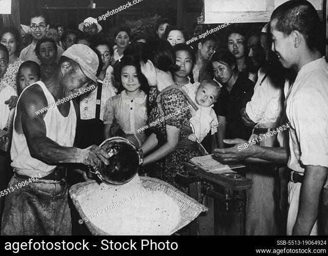 Japanese Receive Flour Milled From U.S. Wheat -- A workman (left foreground) in rationing depot in the Tokyo-Yokahoma area measures a family's tour ration for...