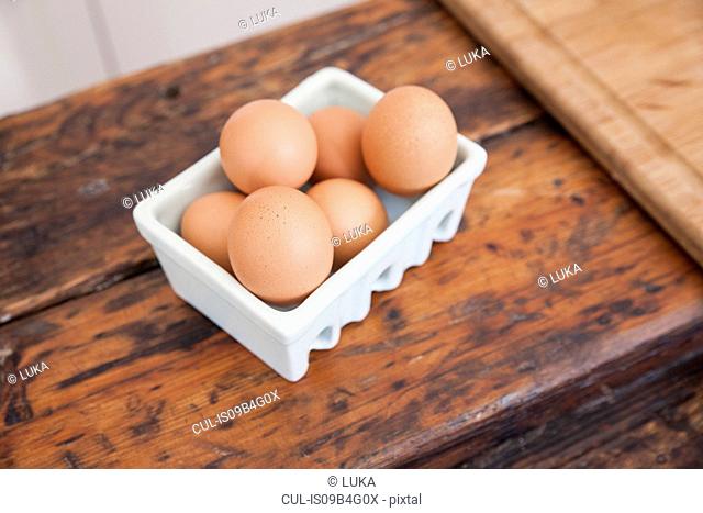 Carton of eggs on wooden kitchen counter
