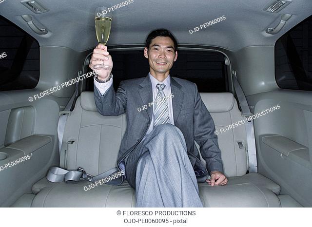 Businessman with champagne flute in limousine