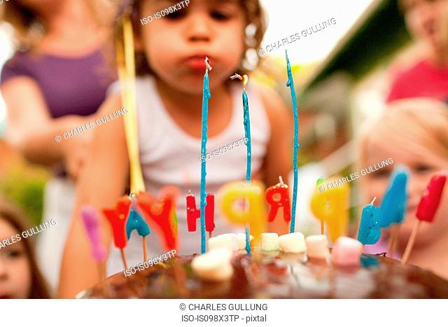 3 year old girl blowing out candles on birthday cake
