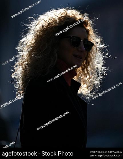 09 February 2023, Hesse, Frankfurt/Main: The curly hair of a woman waiting on a street downtown glows in the backlight. Photo: Arne Dedert/dpa