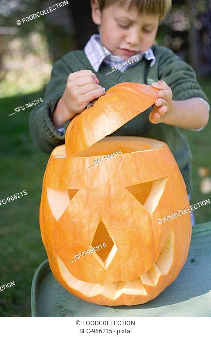 Small boy putting lid on pumpkin lantern