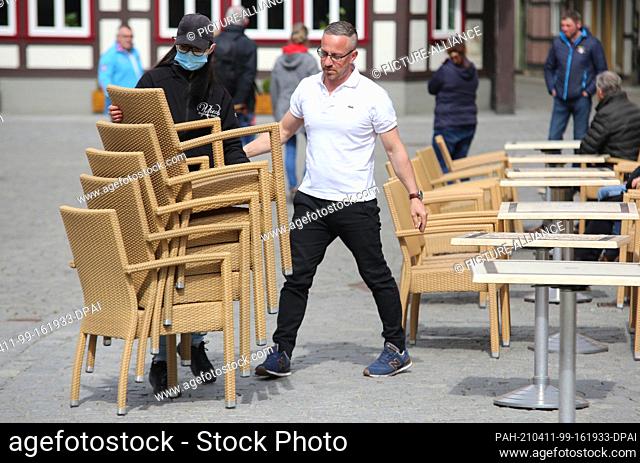 11 April 2021, Saxony-Anhalt, Wernigerode: Tables and chairs are set up in front of a café at noon. For a model test to open the outdoor gastronomy in selected...