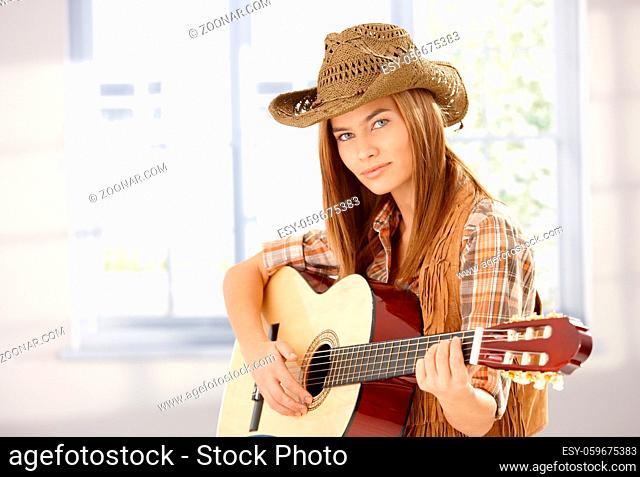 Young attractive female playing guitar in western style