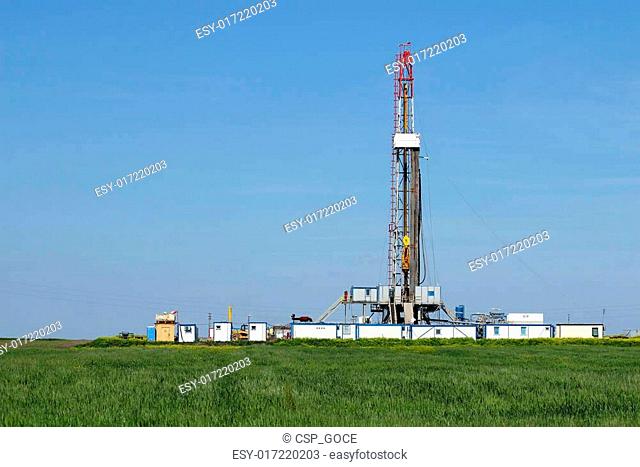 land oil drilling rig on green wheat field