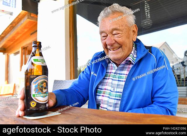Restful old man (92 years) is sitting on his terrace and chatting animatedly, while one hand rests on a beer bottle, drinking alcohol, beer, beer drinker