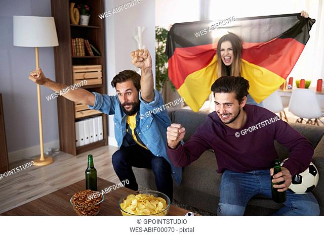 Excited German football fans watching Tv and cheering