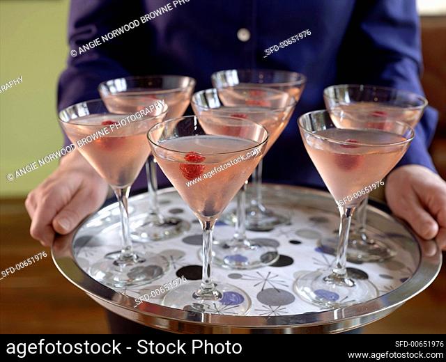 Person holding a silver tray of raspberry Martinis