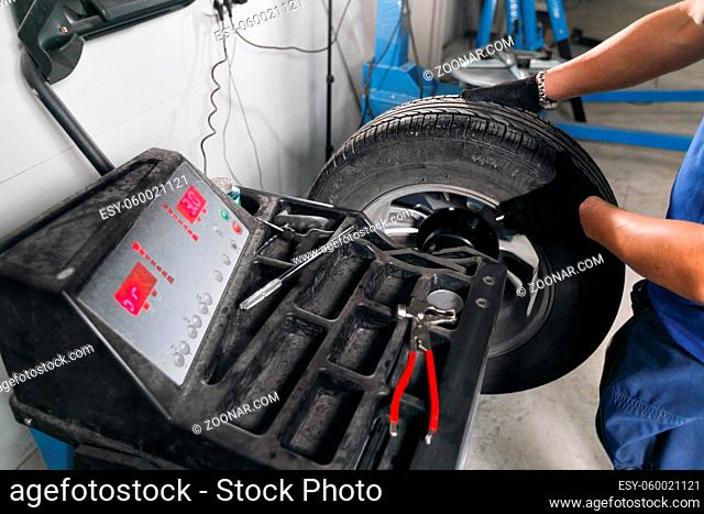 wheel balancing. Mechanic removes car tire closeup. Machine for removing rubber from the wheel disc