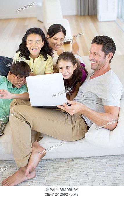 Family using laptop on sofa in living room