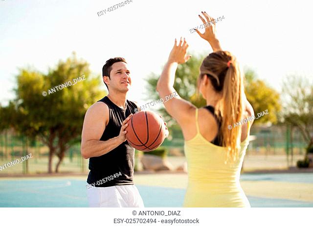 Young Latin man about to score some points on a basketball game against his girlfriend