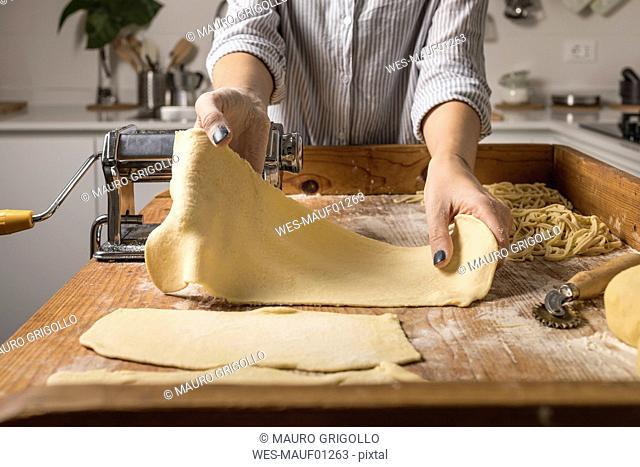 Woman preparing homemade pasta, taking dough