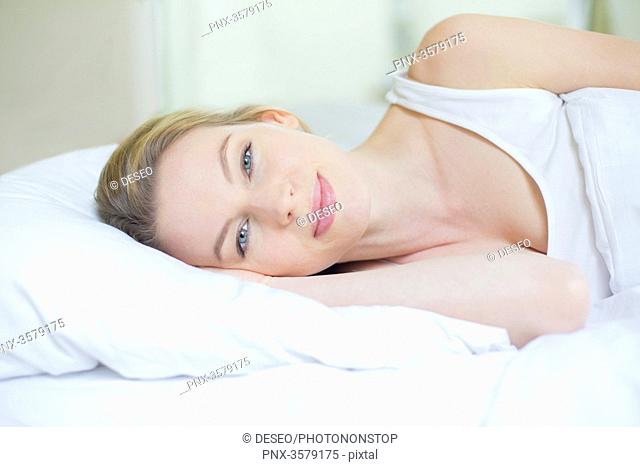Portrait of a pretty blonde woman in bed looking at camera
