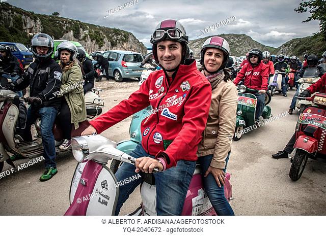 A couple, poses for photographer with his scooter and custom style dressed in Cuevas del Mar beach during Llanes scooters concentration. Asturias