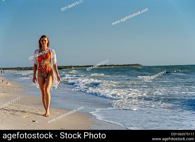 A beautiful brunette bikini model enjoys the weather outdoors on the beach