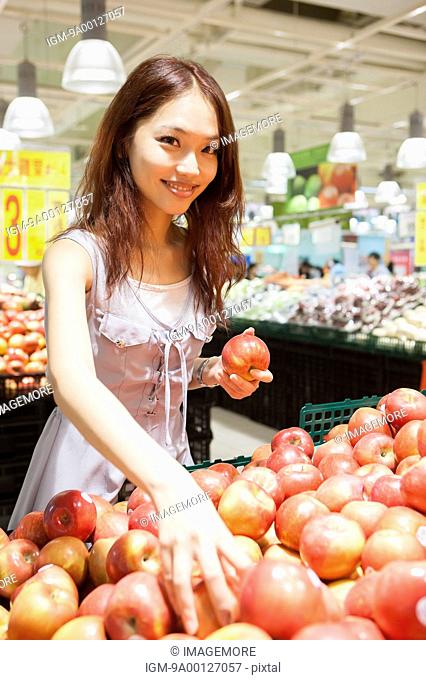 Young woman buying fruits in supermarket