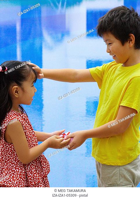 Close-up of a girl giving a gift to a boy at the poolside