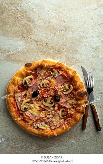 Pizza served with mozzarella cheese, ham, mushrooms and tomato sauce