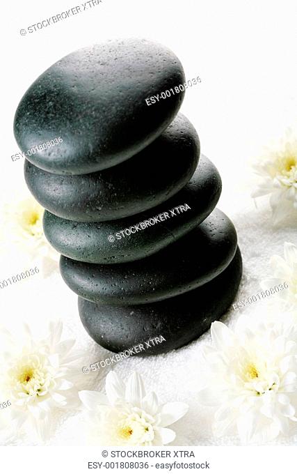 Image of pile of spa stones with flowers near by