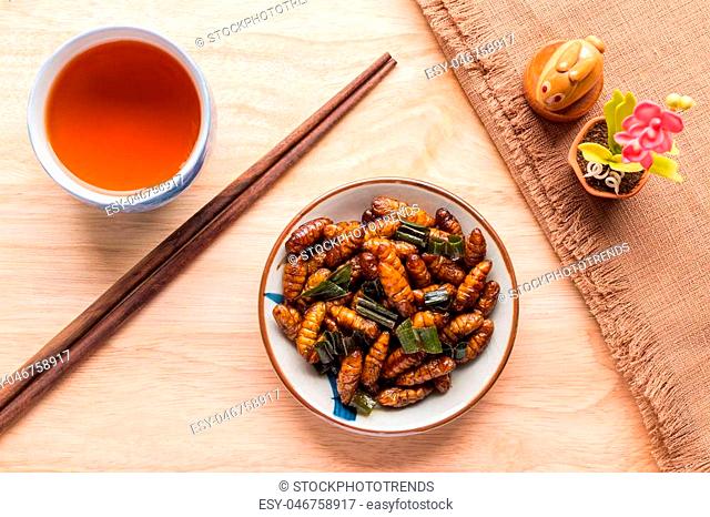 Fried insects - Wood worm insect crispy with pandan after fried and add a light coating of sauce and garnish Thai pepper powder with chopsticks, tea
