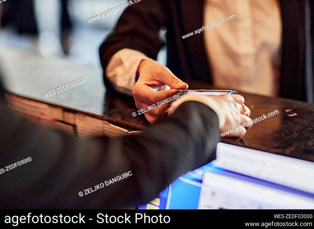 Close-up of woman paying contactless with credit card at reception desk