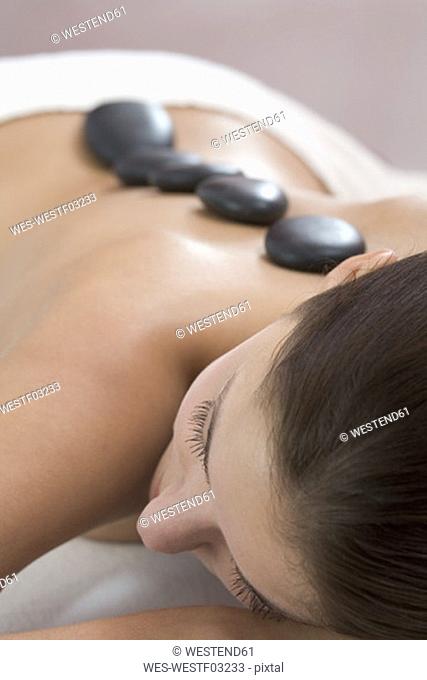 Young woman receiving hot stone massage, close-up