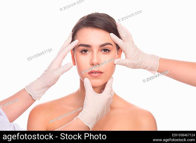 Examining face concept. Beautiful lady looking at camera while her face is being examined by professional doctors cosmetologists