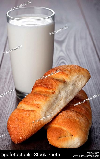 glass of milk and fresh buns on the wooden table
