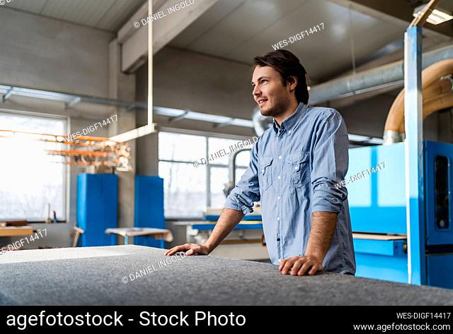 Smiling businessman looking away while standing at industry