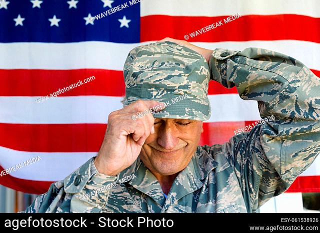 Close-up of smiling caucasian army soldier wearing camouflage cap against flag of america