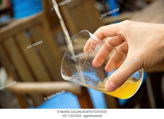 Man's hand serving cider. Asturias, Spain