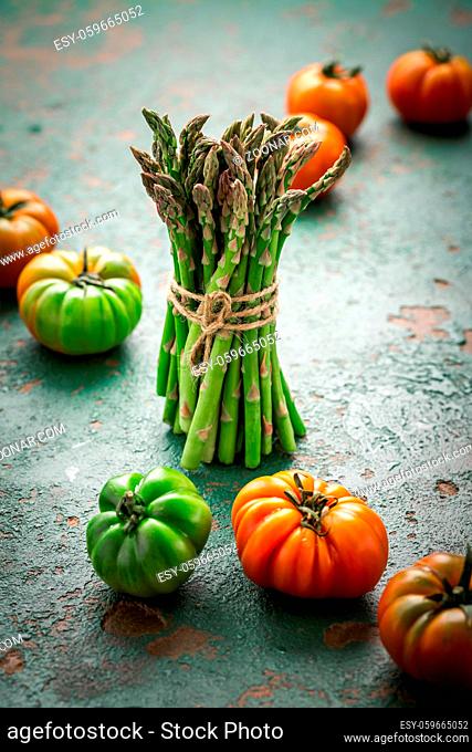 Assortment of organic tomatoes and green asparagus on old kitchen table