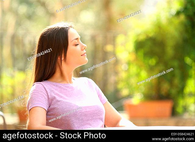 Profile of a woman relaxing enjoying fresh air sitting in a chair in a garden at home
