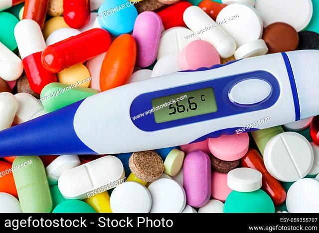 Pills and electronic thermometer (36.6 degrees) - abstract medical background