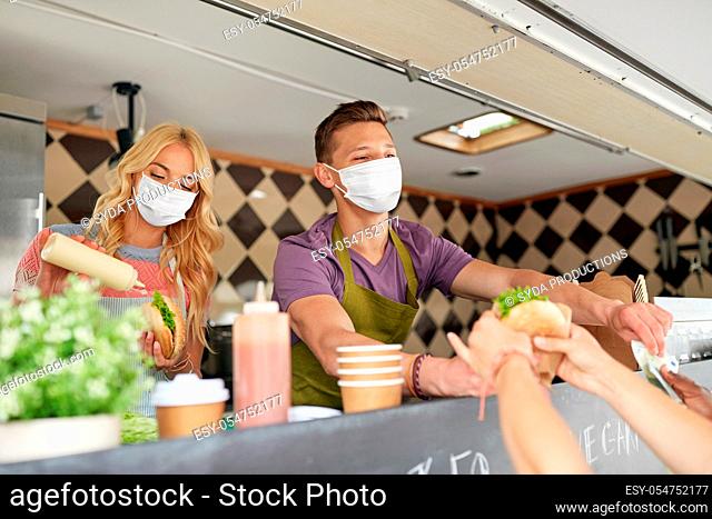 sellers in masks serving customers at food truck