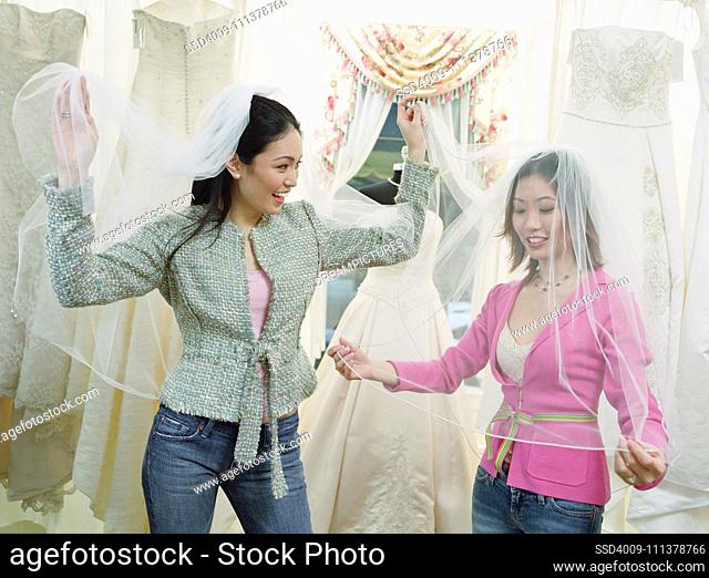 Young women wearing veils in a bridal boutique
