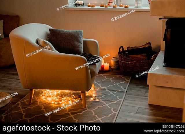 Interior of a cozy room with chair near the fireplace and a basket filled with firewood