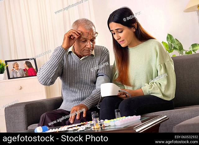Granddaughter checking blood pressure of her grandfather