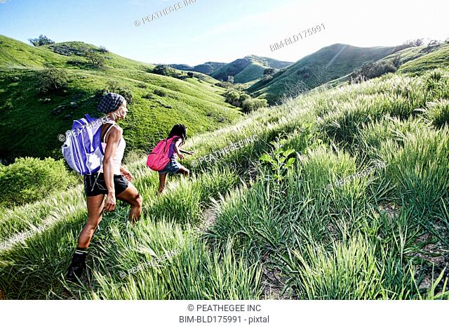 Black mother and daughter walking on rural hillside