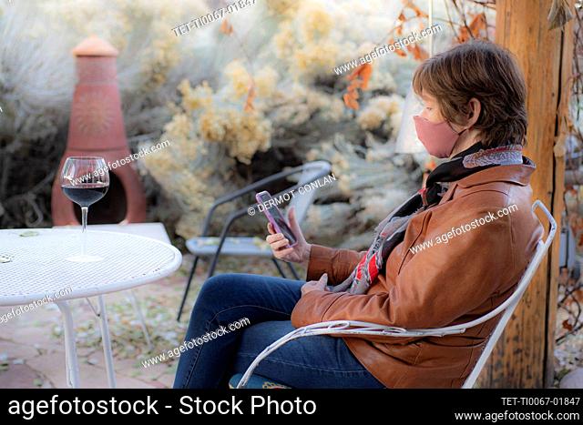 Woman wearing protective face mask sitting on bench