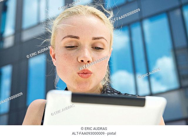 Young woman puckering lips at digital tablet