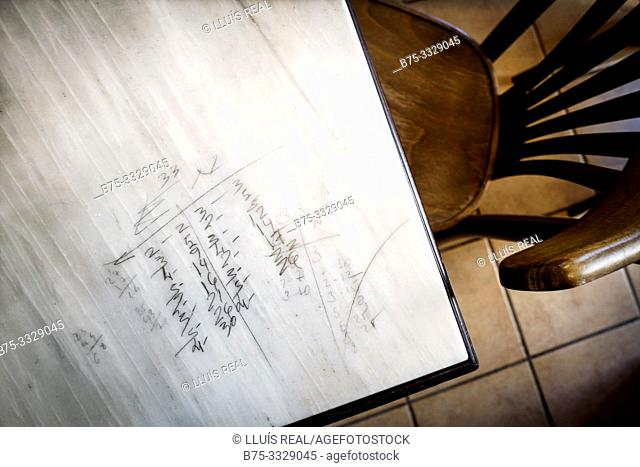 Closeup of a marble table with pencil inscriptions of a domino game, and a chair next to Mahon, Baleares, Spain, Europe