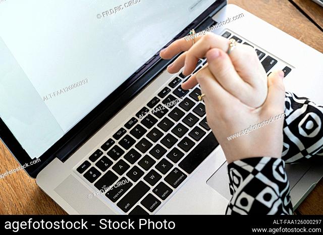 Close-up of woman massaging her hands while working on laptop at home