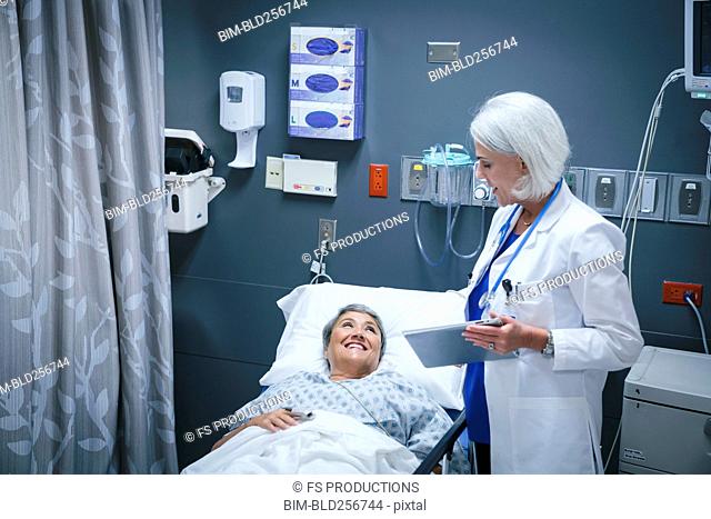Doctor with digital tablet talking to smiling patient in hospital