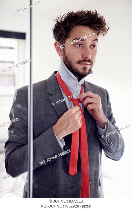 Young man putting tie on, London, United Kingdom