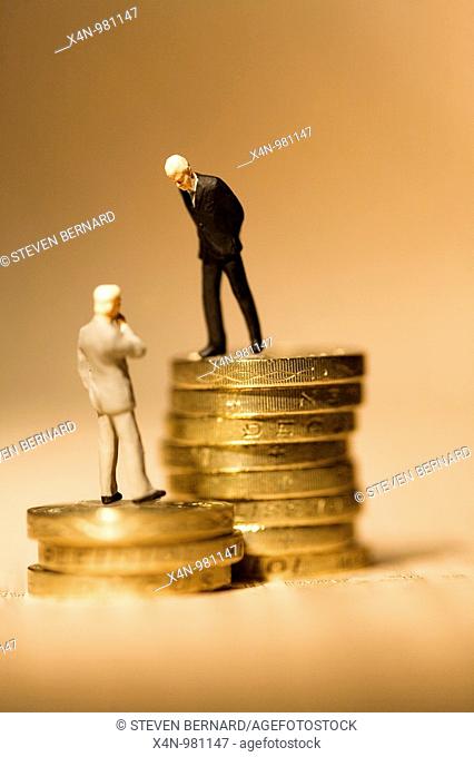 Miniature businessmen standing on coins on financial newspaper  This photo illustrates the vast gap in wages within companies  Senior executives earnings have...