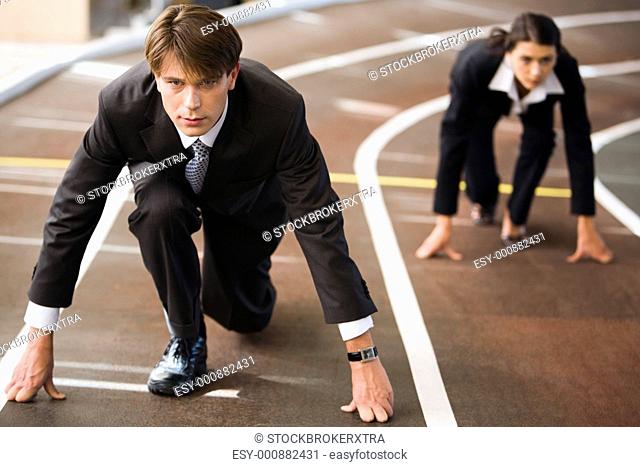 Businessman and businesswoman lined up getting ready for race in business