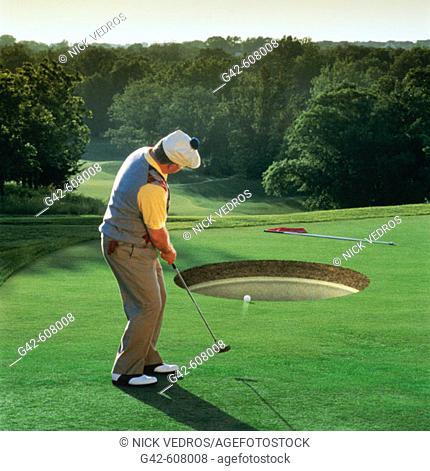 Golfer putting into huge hole